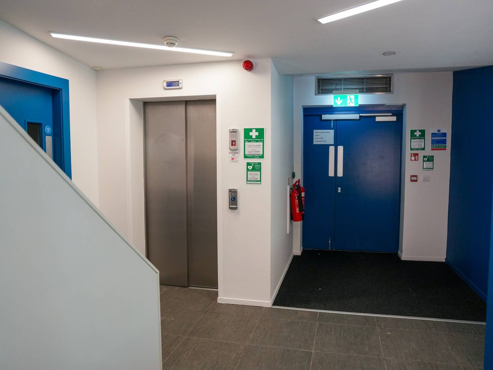 A lift lobby with the evacuation lift, blue fire doors and the stair beyond