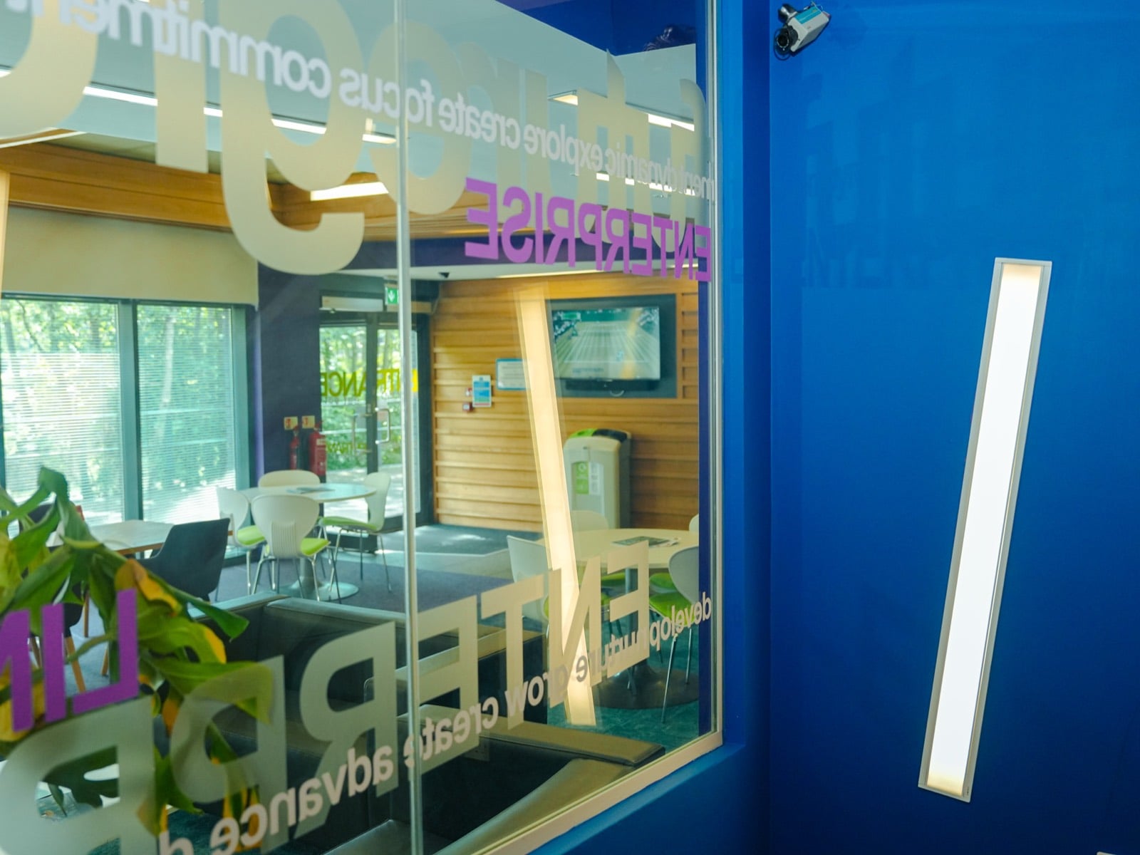 Glass etched with Lincoln Enterprise lettering, looking through into a bright cafe and seating area
