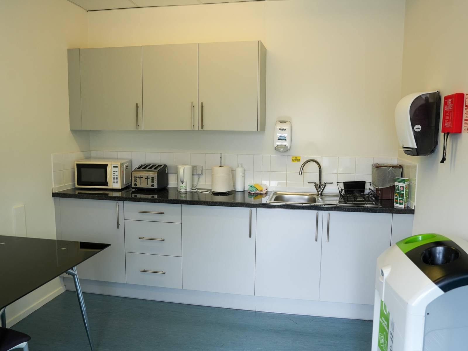 A shared kitchen with a microwave, toaster, kettle and sink along a run of units