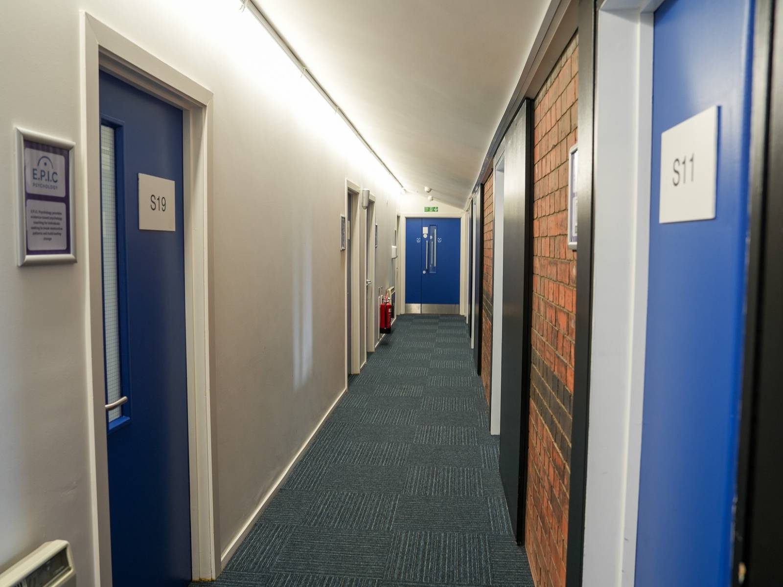 A corridor of numbered blue office doors, S11 and S19, with tenant nameplates beside them