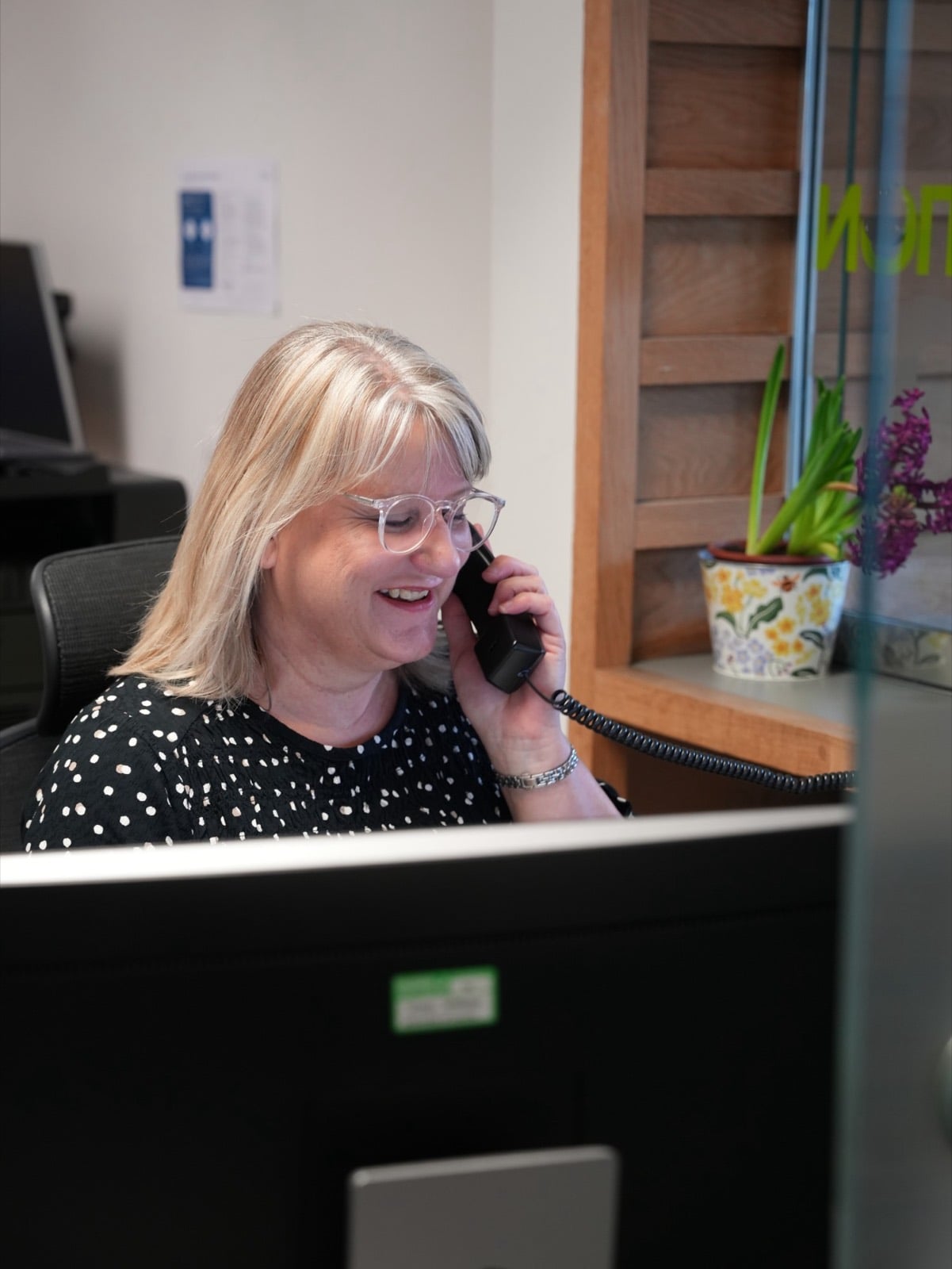 A receptionist smiling as she takes a call at the front desk