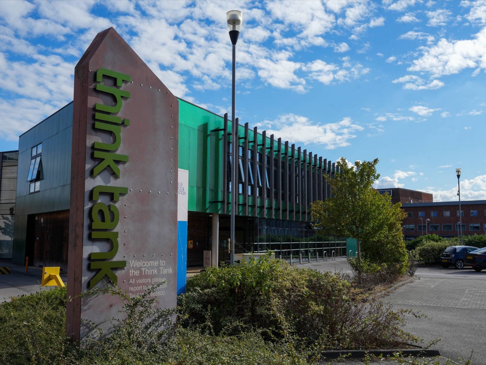 The rusted steel Think Tank sign outside the building, with its green cladding and timber fins behind