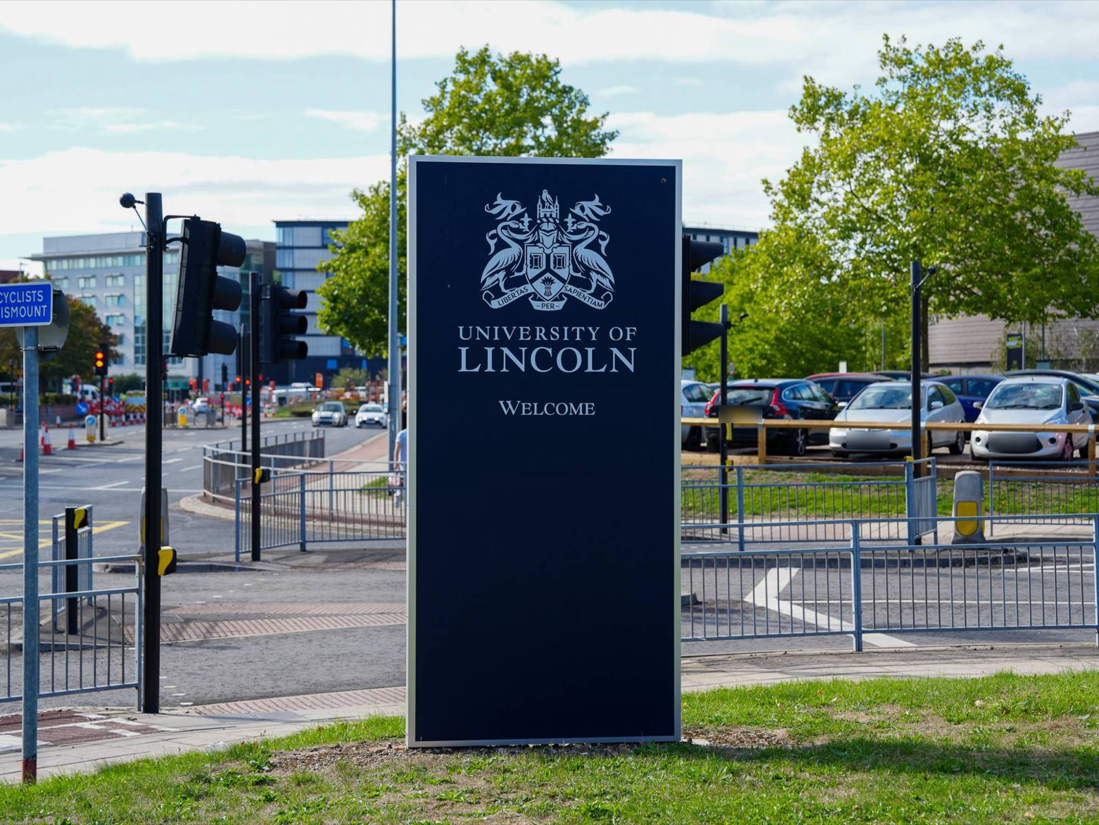 A University of Lincoln welcome sign bearing the crest, at a road junction on the edge of campus