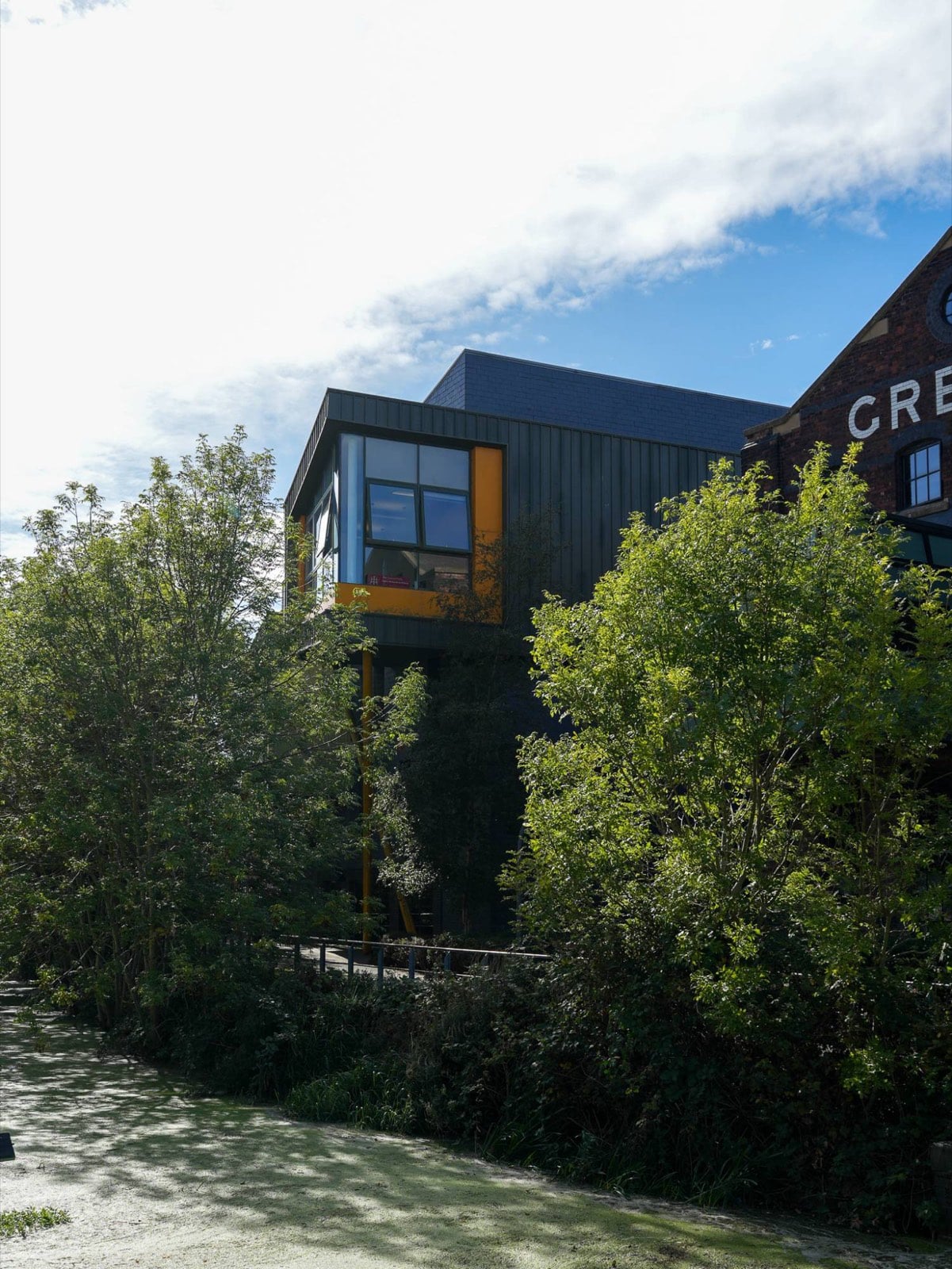 The Enterprise Building, dark-clad with a yellow-framed window box, rising above trees
