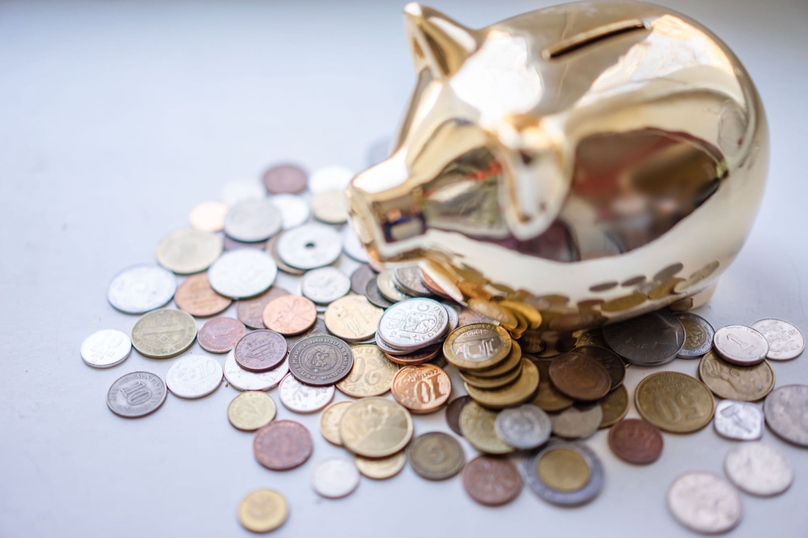 A gold piggy bank beside a scattered pile of coins